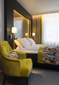 奥斯陆奥斯陆罗森克兰兹托恩酒店的一间卧室配有一张大床和一张黄色椅子