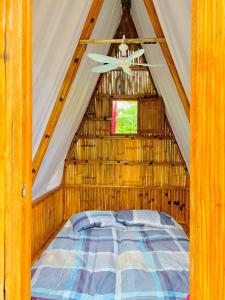 LigaoJodels Paradise的茅草帐篷内的一张床位,配有窗户