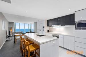 黄金海岸黄金海岸私人公寓 - H公寓，冲浪者天堂的厨房配有白色橱柜和桌椅