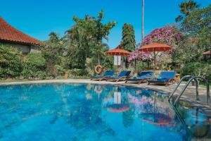 沙努尔巴厘卡塔别墅度假村的一个带蓝色椅子和遮阳伞的游泳池