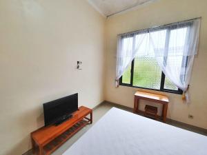 BonorejoGriya Shinta Syariah Solo Mitra RedDoorz的一间卧室设有一张床、一台电视和一个窗口。