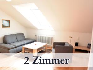 博登斯边的拉多夫采尔Große moderne Ferienwohnung in bester Bodenseelage l 1 Minute zum Bodensee l 3 Zimmer l Vollausgestattete Küche l Sonnenbalkon l WLAN l Willkommen im Apartment Mettnau的客厅配有两张沙发和一张桌子