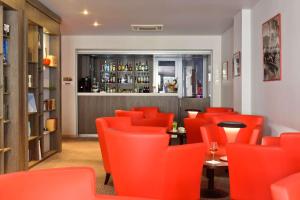 戛纳Best Western Premier Le Patio des Artistes Wellness Jacuzzi的一间设有橙色椅子的餐厅和一间酒吧