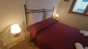 诺托玛丽娜""" Holiday Properties Sicilian Breeze """的一间卧室配有一张带红色床罩和灯的床。
