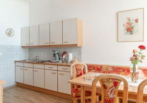 福尔施陶恩特里家庭旅馆的厨房配有白色橱柜和桌椅