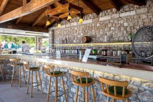帕萨里迪Aegean View Aqua Resort的一个带木凳和石墙的酒吧