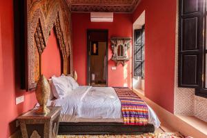 马拉喀什Palais El Roucar的一间卧室设有红色的墙壁和一张带镜子的床