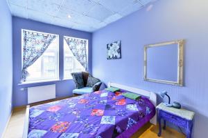 里加中心旅舍的紫色卧室配有一张床和一把椅子