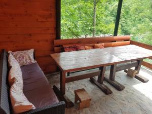科尼茨Potok kuca sa bazenom的门廊上的木桌和沙发