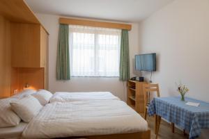 魏森湖Draxl-Hof Ferienwohnungen的一间卧室配有一张床、一张桌子和一台电视