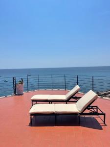 加利波利Salento Palace Bed & Breakfast的俯瞰大海的甲板上设有2把躺椅和1张桌子