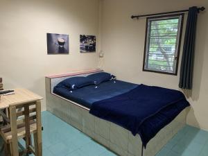 Ban Thumวังตาน้ำรีสอร์ท的一间卧室配有一张带蓝色棉被的床和窗户。