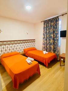 奥萨德蒙铁尔HOSTAL LA CAÑADA RUIDERA的配有橙色床单的客房内的两张床