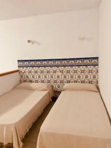 奥萨德蒙铁尔HOSTAL LA CAÑADA RUIDERA的一间设有两张床和一面墙壁的房间