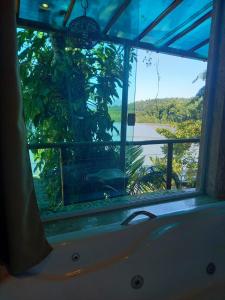 帕拉蒂Pousada Kaetê的带浴缸的浴室窗户,享有河景