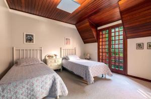 坎波斯杜若尔当Suítes Villa Panorama的一间卧室设有两张床和木制天花板