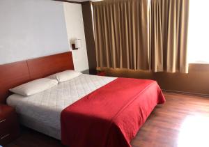 基多Filatelia Suites & Travel的一间卧室配有一张带红色毯子的床和窗户。