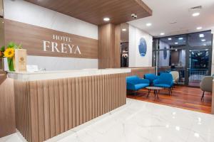 斯特鲁加Hotel Freya的酒店大堂设有fresaya标志和蓝色椅子
