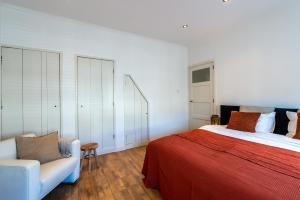 戈伊斯Unieke stadswoning met jacuzzi en sauna max 8 pers的一间卧室配有一张床、一张沙发和一把椅子