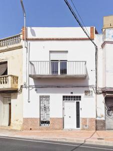 Mareny BarraquetasCASA EN LA PLAYA VALENCIA EL PERELLO的白色的建筑,设有门和阳台