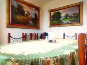 利马利马背包客旅馆的一张桌子,上面有绿桌布和墙上的两幅画