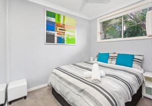 凯阿玛CVU Kiama的白色卧室配有一张带蓝色枕头的大床