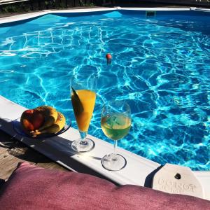 卡尔马Sval källarlägenhet på natur- och havsnära Stensö的游泳池旁托盘上放两杯葡萄酒和水果