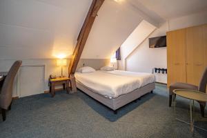 法尔肯堡德博格霍夫弗莱彻酒店及餐厅的卧室配有一张白色的大床和一张桌子