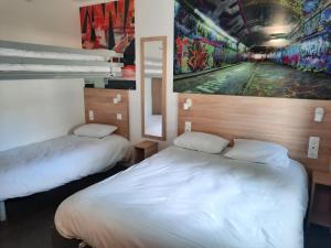 凯恩Kyriad Direct Caen Nord Memorial的墙上画画的房间里设有两张床