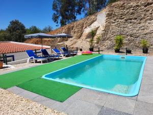 波尔蒂芒Casa Rochinha的一个带绿色草坪和蓝色椅子的游泳池