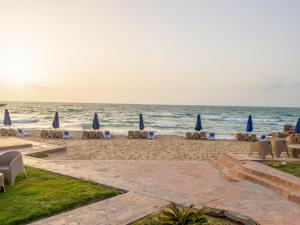 亚历山大Helnan Mamoura Hotel & Events Center的海滩上设有椅子和遮阳伞,还有大海