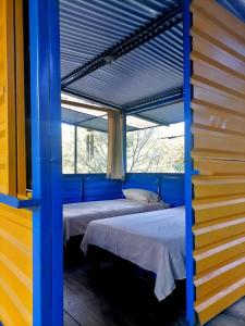 兰金Room in Cabin - Rafting Hut by The River的两张床位于带蓝色和黄色墙壁的客房