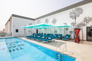 迪拜Ecos Dubai Hotel at Al Furjan的一个带蓝色椅子和遮阳伞的游泳池