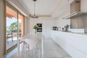 滨海自由城Villefranche Bay View的白色的厨房配有白色的桌子和椅子