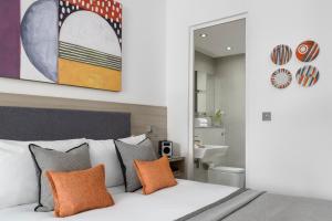 伦敦Templeton Place by Supercity Aparthotels的一间卧室配有带橙色枕头和镜子的床