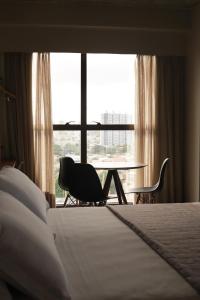 纳塔尔9006 Suites Natal Hotel的酒店客房带一张床、一张桌子和椅子