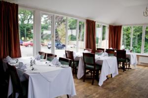 贝灵汉姆里弗代尔豪尔休闲酒店的餐厅设有白色的桌椅和窗户。