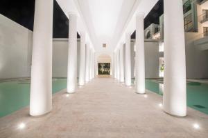 哈马马特巴迪拉成人酒店的建筑的走廊,有柱子和游泳池