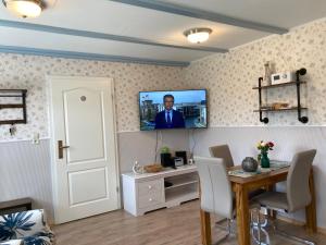 洛默Gästehaus Daheim的客厅配有桌子和墙上的电视