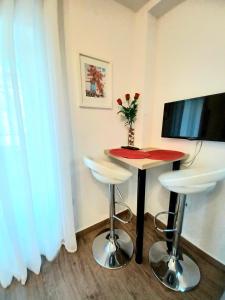 斯普利特Studio Apartmani Pomalo/ Take It Easy的一间设有一张桌子、两张凳子和一台电视的房间