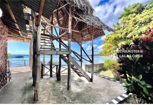 MginiLala lodge Pemba Zanzibar的一个带茅草伞和海洋的度假胜地