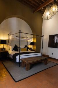 克雷塔罗Hacienda El Salitre Hotel & Spa的一间卧室配有一张天蓬床和一张木桌