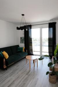 罗兹Apartament Tramwajowa 17B的客厅配有绿色沙发和桌子