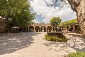 克雷塔罗Hacienda El Salitre Hotel & Spa的一座种有树木的庭院和一座砖砌建筑