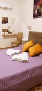 巴勒莫B&B VENTO DEL SUD的紫色的床,配有毛巾和枕头