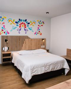 阿亚库乔Platero Hotel的卧室配有一张挂着花壁画的床。