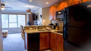 布雷肯里奇Peakside Paradise的厨房配有木制橱柜和黑色冰箱。