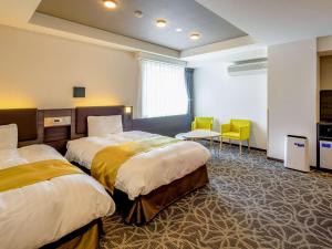 伊势市伊势舒适酒店的酒店客房带两张床和一张桌子以及椅子。