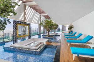 迪拜Paramount Hotel Midtown的一个带蓝色躺椅的游泳池和一个游泳池