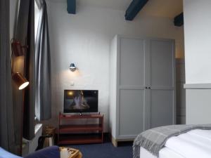 特希尔豪斯霍赫酒店的一间卧室配有一张床和一张桌子上的电视